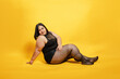 © cesar - Plus size asian model posing on yellow background, embracing body positivity and diversity