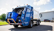 © ON - Studio - Modern garbage truck with extended lift emptying bin in industrial area, waste management
