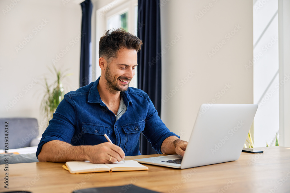 Adult man working at home using laptop taking notes in notepad