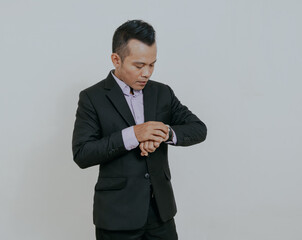 Wall Mural - Handsome Asian boss manager businessman looking at his wristwatch, isolated over white background.