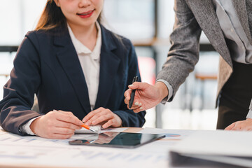 Canvas Print - Two business professionals collaborating on project, reviewing documents and using tablet in modern office setting. atmosphere conveys teamwork and productivity