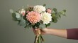 © Nuttaya Nampai - Chic small bouquet of mixed blooms with dahlias, eucalyptus, and carnations tied with twine, displayed in a woman's hand