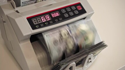 Currency counting machine displays total value of cash at a business