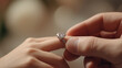 © jpstudio - close up of man hand sliding engagement ring onto woman finger, symbolizing love