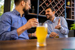© Mediteraneo - Two male friends hanging out at the restaurant and drinking beer.