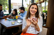 © Mediteraneo - Woman using her phone in the restaurant. Her friends are in the background.