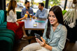 © Mediteraneo - Woman using her phone in the restaurant. Her friends are in the background.