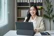 © amnaj - Young businesswoman smiling and working with digital tablet in modern office