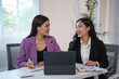 © amnaj - Two asian businesswomen smiling and discussing strategy of working together with digital tablet in the office