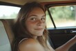 © Ivan - Young woman driving vintage car smiling at viewer on road trip