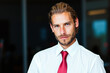 © Minerva Studio - Portrait of businessman wearing white shirt and red tie posing in office