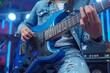 © denklim - Musician performs live on stage playing a blue electric guitar in a lively atmosphere with colorful lights
