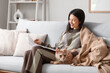 © Pixel-Shot - Pretty young woman with blanket and cute Maine Coon cat reading on sofa at home