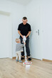 © DSMT - Child boy cleaning the floor at home with dad. Boy washes the floor with a mop for cleaning in the apartment. Children are happy to help with cleaning the house.