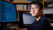 © Jaroon - A young man is sitting in front of a computer monitor, wearing glasses and looking at the screen