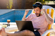 © Javier - Persona trabajando remoto, en la piscina de su casa, festejando una buena noticia que acaba de llegar a su laptop