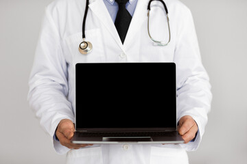 adult male doctor holding laptop computer with black blank screen mock up, isolated over white studi