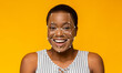 © Prostock-studio - A woman with short hair is smiling while facial recognition technology outlines her features. The bright yellow background enhances the focus on her joyful expression and the tech overlay.