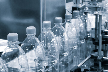 Poster - Bottles of water are being filled at a factory. The bottles are clear and have a plastic cap