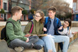 © JackF - Smiling cheerful teenagers talking with each other sitting on stairs on city street