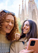 © CarlosBarquero - Vertical. Young only women friend using mobile phone in hands in front of Sagrada Familia in Barcelona. Beautiful caucasian girls at European city enjoying vacation happy smiling. Fun tourism people