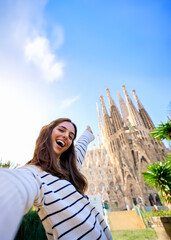 vertical. young funny caucasian women taking a selfie in front of sagrada familia in barcelona. smil
