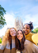 © CarlosBarquero - Vertical. Young only women friends taking selfie in front of Sagrada Familia, Barcelona. Beautiful mixed race girl on street of European city enjoying vacation happy and smiling. Funny tourism people