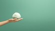 © ahmad - A hand holds a fluffy cotton-like object against a soft green background.