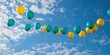 © Abusufyan - Yellow and teal balloons float on a bright, sunny day against a vibrant blue sky dotted with fluffy white clouds.