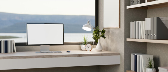 Canvas Print - a computer with a white screen mockup and decor placed on a desk against a large window.