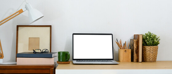 Clean and simple desk with laptop, a cup of coffee, picture frame, and a pencil holder