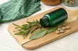 © chaiwat - A green supplement bottle with a leafy herb sprig on top of a wooden cutting board, plant based, wooden cutting board, herbs, supplements