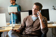 © NDABCREATIVITY - Happy startup business man, programmer, freelancer discussing on mobile phone while looking away.