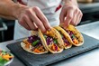© Thedinindu - Chef preparing delicious tacos with shredded chicken, red cabbage, and carrots.