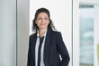 © Westend61 - Smiling mature businesswoman wearing blazer and standing near glass door in office