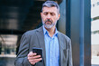 © alfons - Confident businessman using smartphone outdoors,copy space