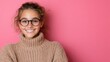 © Iona - A smiling girl in glasses and a snug sweater poses against a pink backdrop, radiating warmth and charm.