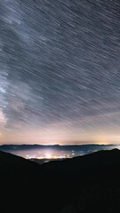 Wall Mural - vertical view of milky way galaxy statrails moving over countryside traffic astronomy time lapse