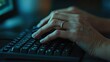 © Arpatsara - A close-up of hands typing on a keyboard in a dimly lit environment, suggesting focus and engagement with technology.