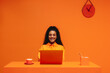 © Jacob Lund - Happy entrepreneur working on laptop in vibrant monochromatic orange office space