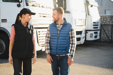 A woman and a man work as truck drivers. The concept of logistics and cargo delivery. In the parking lot