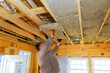 © ungvar - Contractor is carefully placing insulation panels into ceiling framework of newly built house.