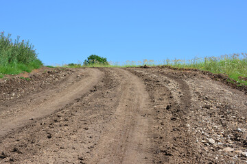 Wall Mural - Dirt road with a trail track is going up the hill with blue sky