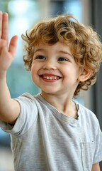 Wall Mural - A young boy is smiling and waving at the camera