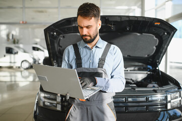 Fototapete - Mechanic Uses a Computer with an Augmented Reality Diagnostics Software. Specialist Inspecting Car's Engine to Quickly Spot Broken Components. Premium Car Service