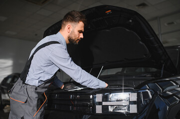 Leinwandbilder - Friendly mechanic in modern car repair shop with car. Professional technician checking vehicle diagnostics and maintenance. Concept of automotive industry and customer service