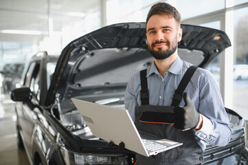 Leinwandbilder - Friendly mechanic in modern car repair shop with car. Professional technician checking vehicle diagnostics and maintenance. Concept of automotive industry and customer service