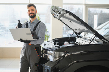 Leinwandbilder - Auto mechanic using computer diagnostic program while repairing car in workshop