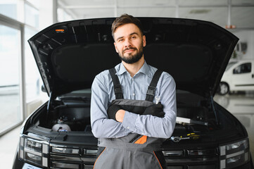 Leinwandbilder - Friendly mechanic in modern car repair shop with car. Professional technician checking vehicle diagnostics and maintenance. Concept of automotive industry and customer service
