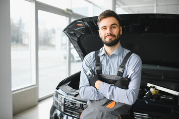 Leinwandbilder - Friendly mechanic in modern car repair shop with car. Professional technician checking vehicle diagnostics and maintenance. Concept of automotive industry and customer service